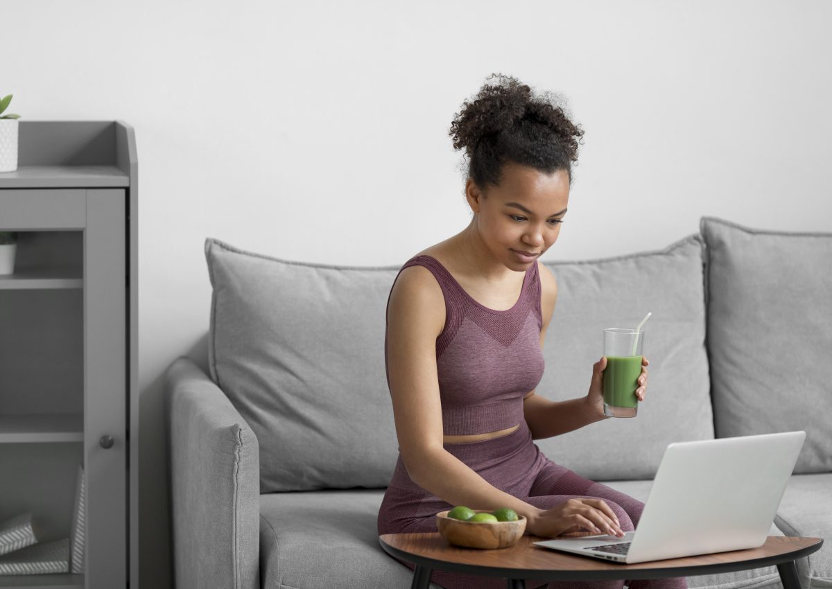 fitness-woman-having-fruit-juice-while-using-laptop